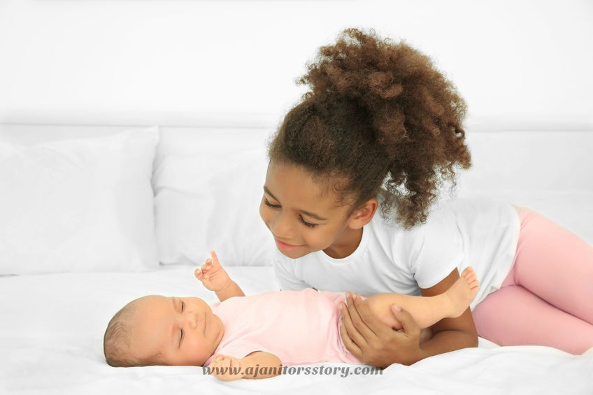 Why and how to wash sheets and towels with your cleaning comapany. Cute baby on bed with her elder sister.